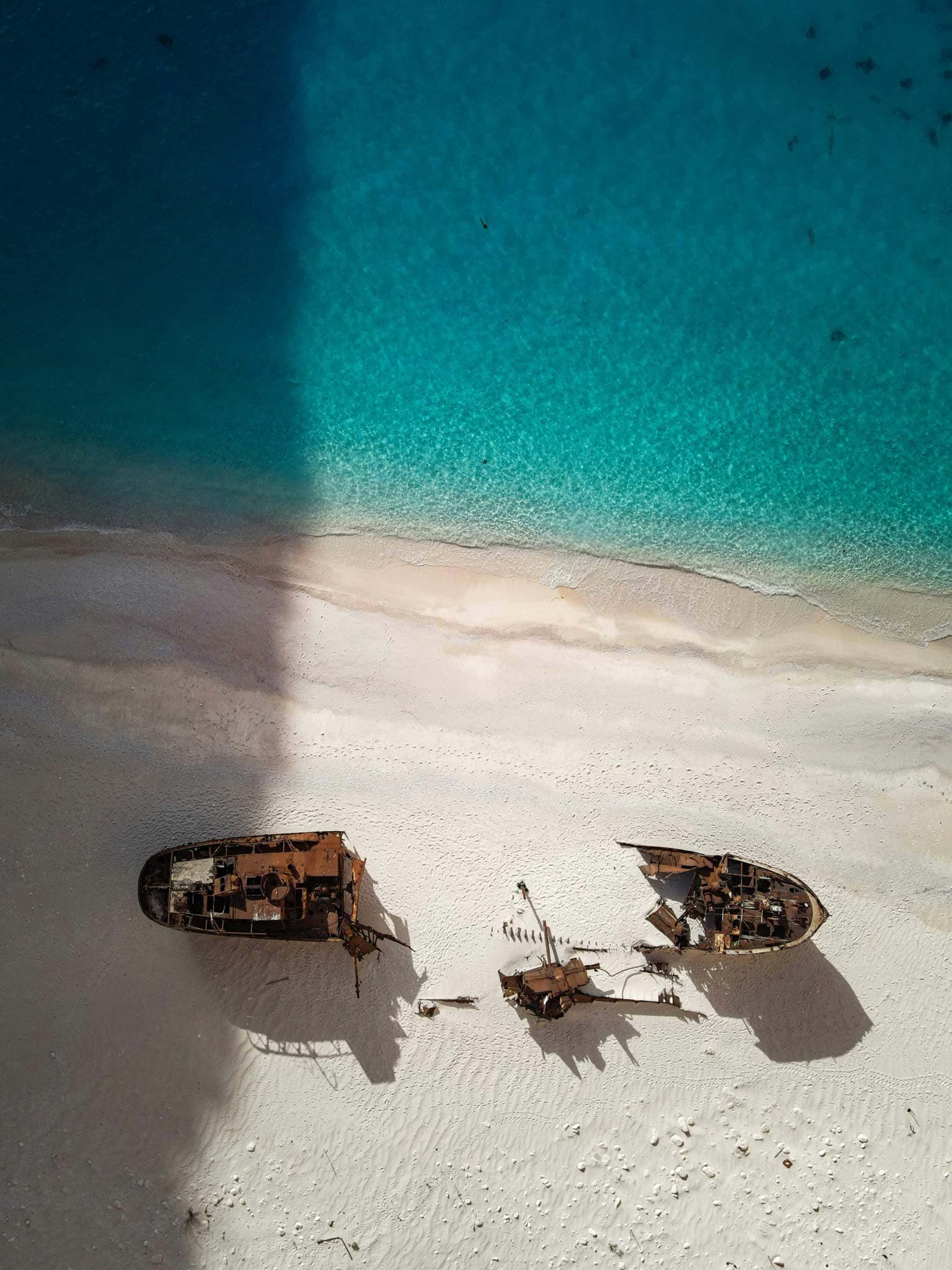 Aerial view of two shipwrecks on a white sand beach