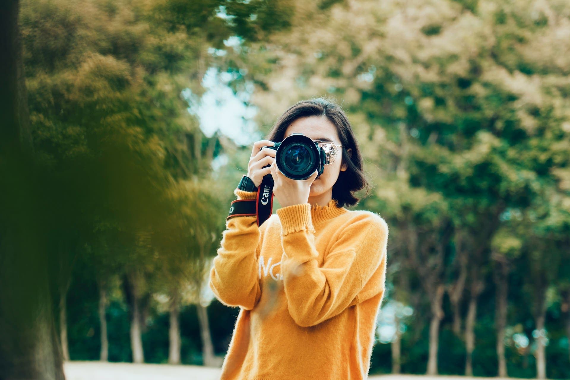 Photographer in a park holding a DSLR camera up to take a photo
