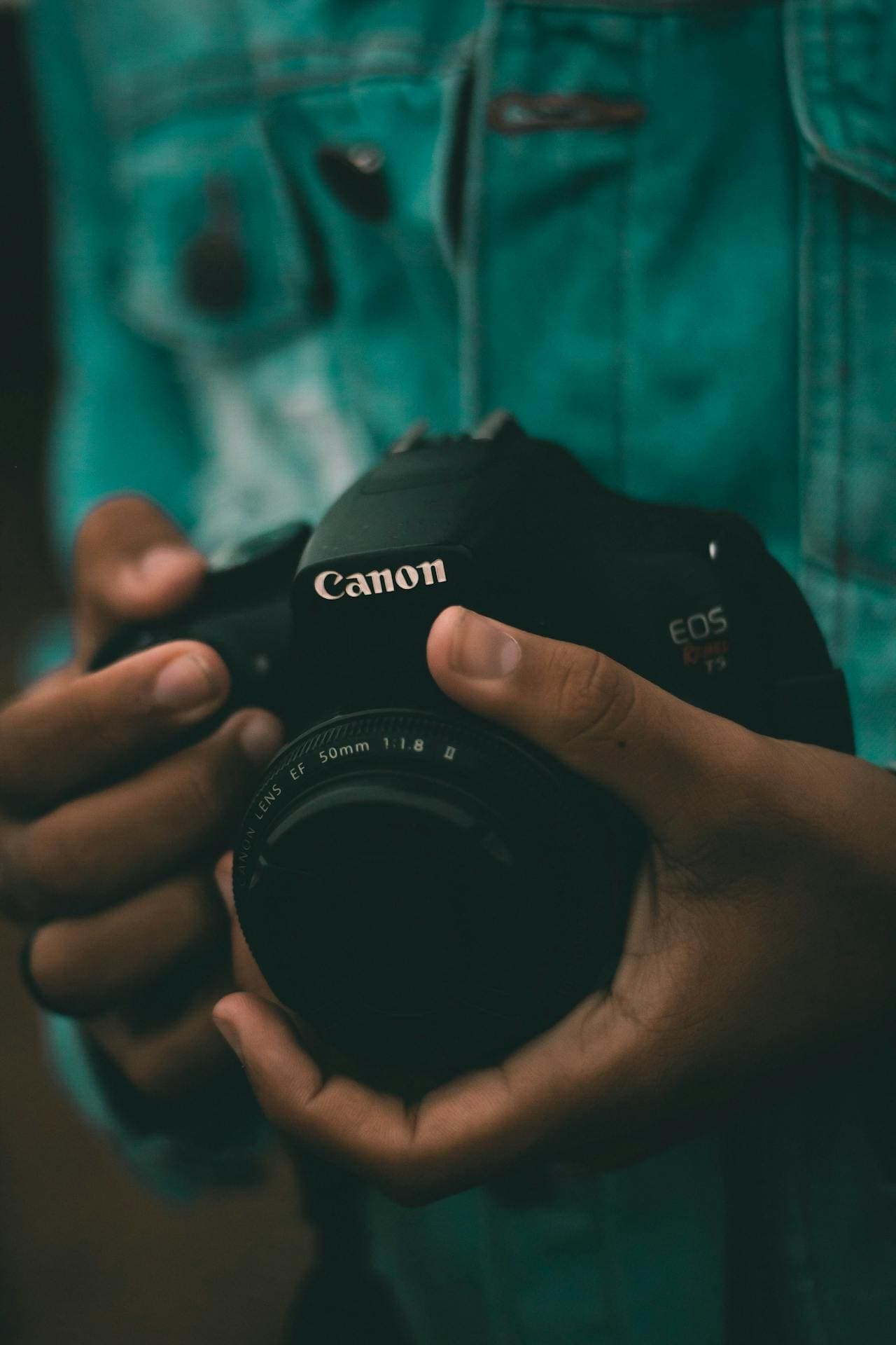 Close-up of hands holding a Canon DSLR camera