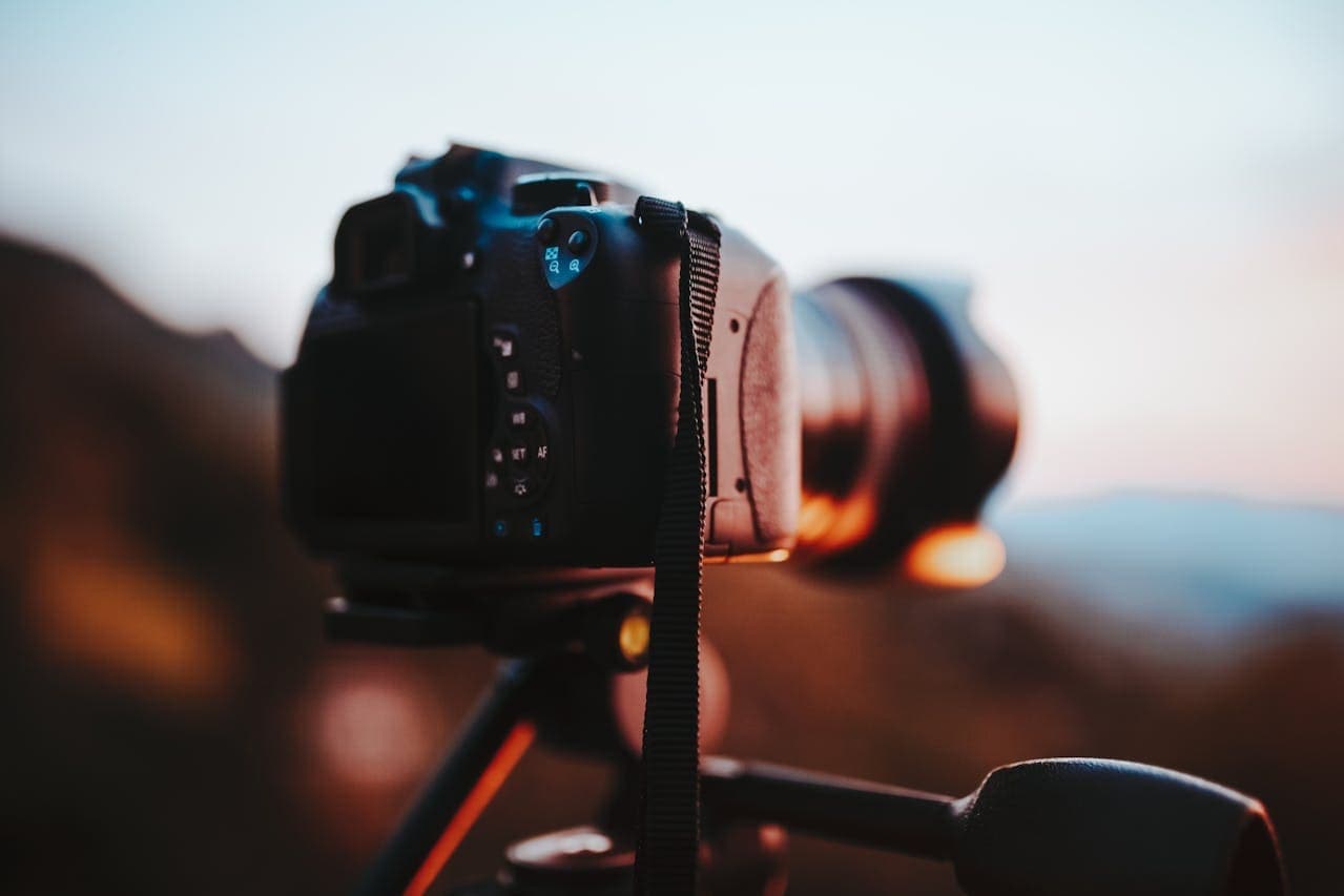 DSLR camera mounted on a tripod capturing a sunset landscape